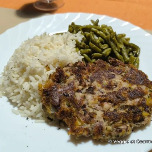 Assiette avec un steak végétarien accompagné de riz et d'haricots verts