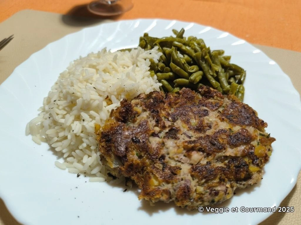 Assiette avec un steak végétarien accompagné de riz et d'haricots verts